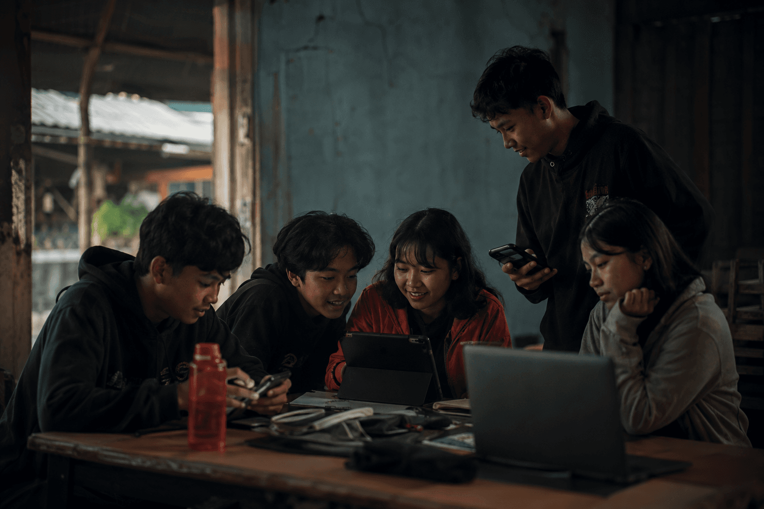 Sekelompok remaja belajar bersama menggunakan telepon, tablet, dan laptop.